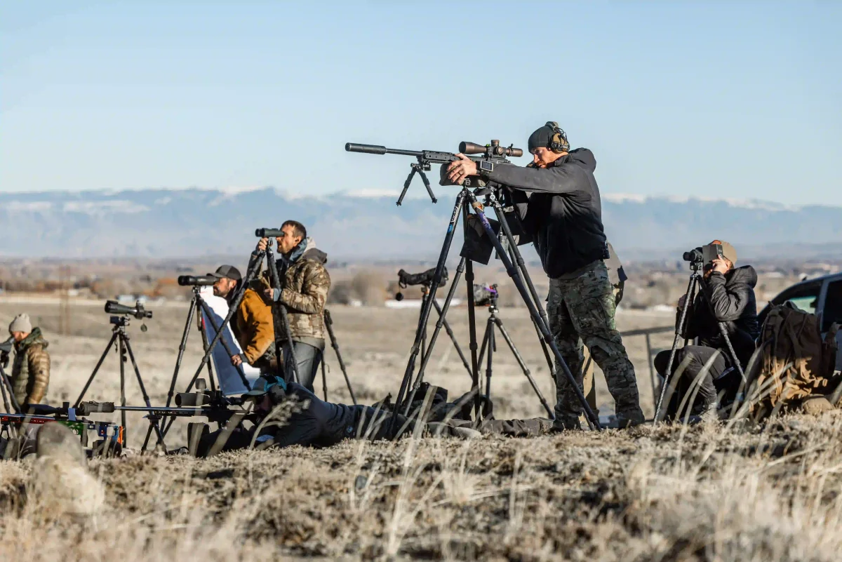 Shooters and spotters working from tripods on a mountain range